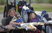 A little rain doesn’t disrupt vendor Cindy Roberts, above, her dog P.J. and her step-daughter Riley Wilson, 6, as they sell T-shirts at the first Lawrence Flea market of the season on April 7 at Teepee Junction.
