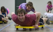 Seven-year-old Caroline Bork pushes her father, Reid, on a scooter as the two compete in the Scooter Swimming event during the Quail Run Girl Scouts' annual father-daughter event on Sunday in Building 21 at the Douglas County Fairgrounds. The theme of this year's event was the Olympics.