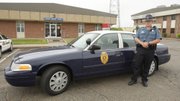In this April 5, 2012 photo, Kansas Highway Patrol trooper Matt Mullen stands by the new retro patrol car at their headquarters in Wichita, Kan. Trooper Matt Mullen, who is based in Wichita, said he has been getting quizzical looks from children and second glances from adults since being assigned one of the retro 2011 Crown Victoria models.