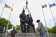 Tony Housley, left, and Toben Mosier place a bronze sculpture of an American soldier and a South Vietnamese soldier at the Vietnamese American Community Memorial in Veterans Memorial Park Friday, Apr. 20, 2012, in Wichita, Kan. Babs Mellor, the lead sculptor on the project, said the statue depicts the side-by-side partnership of American and Vietnamese soldiers.