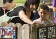 Leah Scheck and her son Caleb, 9, of Topeka, look at signs made from old license plates during the 51st annual Art in the Park on Sunday at South Park.