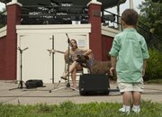 Two-year-old Liam Sturm watches Nicolette Paige perform. Art in the Park featured art, music, food and a concurrent flying disc competition for dogs.