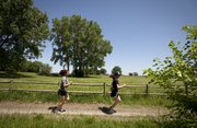 Lawrence residents Lori White, left, and Ricki Endsley take off around a turn as they run on the north river trails on Thursday, May 10, 2012.