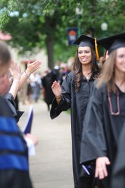 Baker School of Nursing graduate Lauren Jo Torrez reaches up to high-five a professor as undergraduates file through two lines of faculty on their way to commencement.