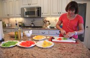 Ivy Travis works on her mother-in-law's spinach salad recipe, using fresh spinach, sweet peppers, mushrooms, bacon, and finishing off with a mustard vinegar based dressing.