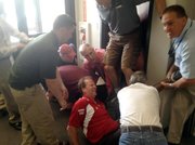 This photo provided by WIBW-TV shows station employees holding down an unidentified man until police arrive Wednesday, May 23, 2012, in Topeka, Kan. WIBW-TV reported the knife-wielding man broke into the television station and stabbed two sales employees. The suspect and victims were taken to a hospital for treatment. None of their injuries were considered serious.