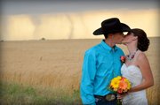 In this May 19, 2012, photo provided by Cate Eighmey, Caleb & Candra Pence pose for a wedding photo as a tornado swirls in the background after they were married in Harper County, Kan.