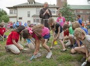 The Rev. John Schmeidler, of St. John the Evangelist Catholic Church, watches as St. John’s students participate Thursday in a ceremonial dig on a piece of property planned for a new middle school. The addition, pending approval, will be in the empty lot beside 1229 Vt., between the current school and the church.