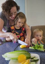 Kris Adair helps her daughter Audrey Montgomery, 4, cut a pepper for a Salad on a Stick. Audrey's sister Maurene Montgomery, 2, helps at right.