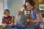 Maurene Montgomery, 2, center, pours a fruit sauce on a fruit bread pudding dish she was helping her sister Audrey, 4, left and her mother Kris Adair, prepare at their home, Friday, June 1, 2012.