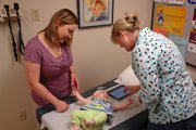 Dr. Jennifer Brull, right, uses an electronic health record system to record her patients’ health information via a tablet computer that goes with her wherever she is administering care. With the statewide health information exchange, which goes live July 1, she will be able to access records that her patients have at other facilities connected to the exchange, such as other hospitals, specialists or laboratories.