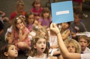 Five-year-old Gillian Sellet, center, lights up as she and other young children gather to look at classic pieces of art while listening to poetry during Kidsapalooza June 4 at the Lawrence Public Library. Kidsapalooza is one of many events hosted by the library that are designed to keep kids intellectually engaged during the summer months.