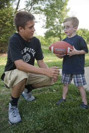Dallas Hunt, 14, works with Cooper Keffer, 4, on how to throw a spiral pass. The two Lawrence residents have become like brothers after Dallas researched Cooper's Cause Foundation and choose to donate $300 he found in a parking lot to the foundation which helps families with pediatric heart patients like Cooper. Dallas raised additional money for the foundation by collecting donations in his school and neighborhood.
