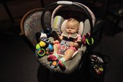 Ella Cate Vise, 4 months, sits in her carrier complete with an array of toys to plays with last week at a support group for new mothers at Lawrence Memorial Hospital. A car seat is a necessity, but use care when looking at after-market additions.