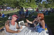 Michael Laing and Jules Richardson, of Lawrence, settle in with a portable fan and a game of cards during the Lawrence Originals Party in the Park Wednesday at Watson Park, Seventh and Kentucky streets. Food was available from Lawrence Originals restaurants with music and children’s activities until the evening fireworks display.