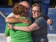 Tom Sullivan, center, embraces family members outside Gateway High School where he has been searching franticly for his son Alex Sullivan who celebrated his 27th birthday by going to see "The Dark Knight Rises," movie where a gunman opened fire Friday, July 20, 2012, in Aurora, Colo.