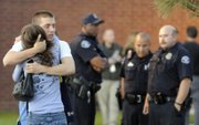 Eyewitness Jacob Stevens, 18, hugs his mother Tammi Stevens after being interview by police outside Gateway High School where witnesses were brought for questioning Friday, July 20, 2012 in Aurora, Colo. A gunman wearing a gas mask set off an unknown gas and fired into the crowded movie theater killing 12 people and injuring at least 50 others, authorities said.