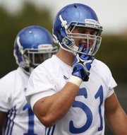 Kansas linebacker Anthony McDonald pops in his mouth guard as he and the linebackers gather for drills during practice on Thursday, Aug. 2, 2012.