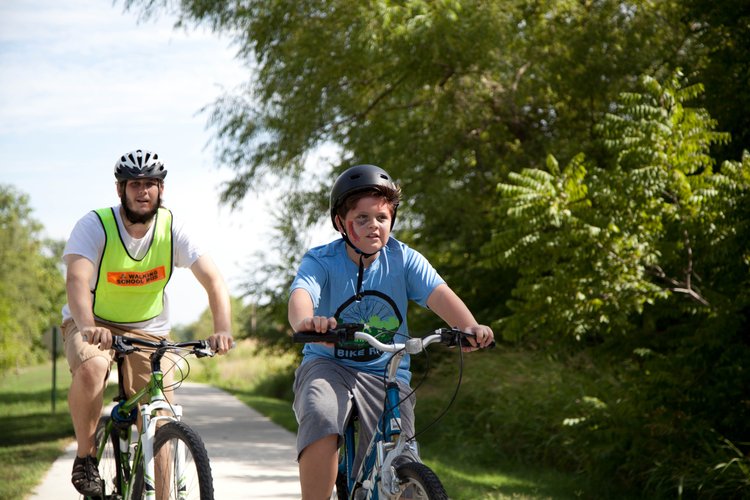 Stephen Mason, a ZOMBIE route leader rides with zombie. Staff and volunteers wore bright Walking School Bus vests to promote safety and guide participants along the trail.