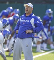 Strength and conditioning coach Scott Holsopple calls out stretches as the Jayhawks get loose for practice on Wednesday, Aug. 15, 2012.