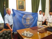 Lawrence Mayor Bob Schumm, left, receives the official flag of the Municipality of Messolonghi, Greece, from Mayor Panagioeis Kaesoulis, holding flag at right. With them are other members of the Sister City delegation to Iniades, Greece. Messolonghi is responsible for the administration of the area of Iniades.