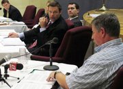 Kansas Secretary of State Kris Kobach, center, questions Joe Montgomery, lower right, a Manhattan, Kan., resident, during a meeting of the State Objections Board, Thursday, Sept. 13, 2012, in Topeka, Kan. The board includes Kobach and, behind him, Attorney General Derek Schmidt and is reviewing Montgomery's objection to the state listing President Barack Obama on its November election ballot.