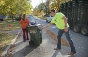 Lawrence resident Jessica Houk, left, gets her new 65-gallon city residential trash cart delivered on Monday by Tyler Green, an employee with Buckeye Diamond Logistics, which was contracted by the city to deliver the new containers. Crews delivered about 1,000 green plastic trash carts to the curbs of Lawrence residences Monday, and another approximately 19,000 are on the way as part of the city’s program to require residents to use city-issued trash carts instead of cans or bags.