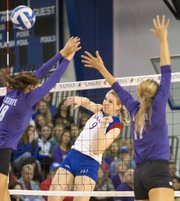Kansas' Caroline Jarmoc (9) hits a shot down the line, avoiding a pair of Kansas State blockers during their volleyball match Wednesday, Oct. 17, 2012, at Horejsi Center.