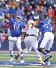 Kansas quarterback Michael Cummings heaves a pass as Texas defensive tackle Brandon Moore is fended off by KU lineman Randall Dent during the first quarter on Saturday, Oct. 27, 2012 at Memorial Stadium.