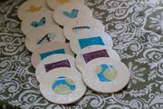 A fabric scrap shape-matching game with fabric shapes glued onto round wooden tiles can help toddlers learn while playing.