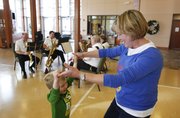 Kids First Preschool teacher Carol Dobbins laughs with Quinn Head as the two dance the polka during a performance by the River City Reeds on Nov. 30 at the preschool.