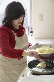 Nechama Tiechtel drops a spoonful of shredded potatoes and onions into a skillet of oil to make latkes at Lawrence's Chabad Jewish Center. Tiechtel makes latkes — a treat traditionally enjoyed during Hanukkah — the old-fashioned way, but there are also recipes for making them with zucchini or other vegetables.