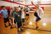 Seventh-grader Ted Carttar gives a final karate kick after high-stepping across the gym floor, while Evan Stewart, left, Rowan Laufer and Tom Richardson observe and measure the attempt during the Smart Strength workout Thursday at Liberty Memorial Central Middle School. About 50 students regularly participate in the after-school workout, which employs a plyometric training regimen.