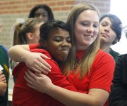 Free State High seniors A'Liyah Rogers, left, and Courtney Parker hug after signing their national letters of intent on Wednesday, Dec. 12, 2012, in the commons area at Free State High. Rogers will be playing softball for Bradley University while Parker will be playing for Benedictine College.