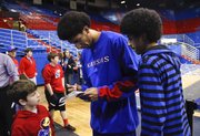 Donovan Young, right, watches as his older brother, KU forward Kevin Young signs an autograph for Trentyn Harris of Frontenac, Kan., after Tuesday's game against Richmond at Allen Fieldhouse.