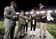 National team quarterback Dayne Crist (10) of Kansas holds up the trophy as head coach Dick Vermeil, right, and NFLPA Executive Director DeMaurice Smith celebrate after the NFLPA Collegiate Bowl on Saturday, Jan. 19, 2013 in Carson, Calif. (Ric Tapia/AP Images for NFLPA)