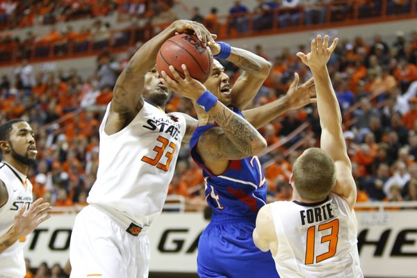 Kansas guard Travis Releford is fouled by Oklahoma State guard Marcus Smart during the first half on Wednesday, Feb. 20, 2013 at Gallagher-Iba Arena in Stillwater, Oklahoma. In front is OSU guard Phil Forte.