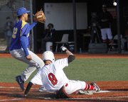 Lawrence High junior Easton Barnes (9) slide safely into home plate to score in the Lions' game against Olathe South on Thursday, April 4, 2013 at LHS.