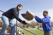 Kansas University sophomore Corey Boucher, St. Louis, Mo., right, tosses a bag of mulch to John Curran, Olathe, at the Lawrence High School football stadium during the third annual Big Event volunteer service day on Saturday. Nearly 3,000 KU students and staff members spread out across Lawrence performing volunteer duties such as mulching, weeding and planting flowers.