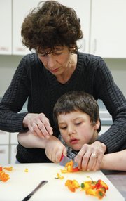 Bryce Fuller, 6, helps Family Promise volunteer Sula Teller chop peppers for a recent dinner in the kitchen of First United Methodist Church, 946 Vermont St.