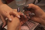 Tracy Meisenheimer of Nails by Tracy gives Barb Rollins, Lawrence, a nail art manicure — featuring multiple polish colors and glitter — at her salon in the Hillcrest Shopping Center.