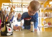 Three-year-old Payton Pringle, Lawrence, concentrates as he paints a car blue at Sunfire Ceramics, 1002 New Hampshire St. Payton was painting the car for a Mother's Day gift.