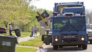 Charles Barnes, operator of one of the city's automated trash trucks, uses a mechanical arm to lift city trash bins off the street in the Prairie Park Neighborhood. The vehicle requires only one crew member.