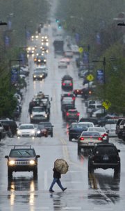 A pedestrian is shielded by an umbrella while crossing Massachusetts street as a mixture of rain and sleet falls over downtown on, Thursday, May 2, 2013. Nick Krug/Journal-World Photo