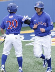 Kansas University infielder Justin Protacio (20) greets Jordan Dreiling at home plate after Dreiling scored on a hit by Ka’iana Eldredge during the Jayhawks’ 6-5, walk-off victory against Baylor on Saturday, May 4, 2013, at Hoglund Ballpark.