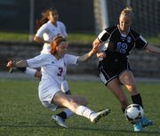 Lawrence High's Addison Campbell, left, pushes the ball past Leavenworth's A.J. Hochard during the first half, Thursday, May 9, 2013 at Lawrence High School.