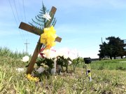 A cross, flowers and a picture of 18-month-old Lana-Leigh Bailey, whose body was found Saturday evening in Osage County, sit at the intersection of Georgia and Highway 68 In Ottawa Monday. Police say they believe Lana-Leigh was killed, along with her mother and two other men, at a farmstead at 3197 Georgia Road.