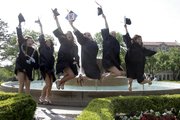 Chi Omega sorority members jump in front of the Chi Omega fountain for family members during commencement ceremonies Sunday, May 19, 2013.
