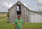 Mike Yoder/Journal-World Photo.An old barn, a house and several outbuildings still stand on the farmstead of George Hunsinger's grandfather, who bought the Wakarusa Township property in 1918. Hunsinger, picture in front of the farmsteads original barn, lives on adjacent property across the road and now rents the house on the property and farms the land.