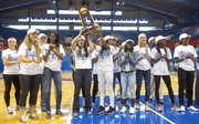 Members of the Kansas University women's track team hold up the national championship trophy in front of a small crowd gathered inside Allen Fieldhouse on Sunday to welcome the team home.
